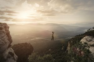 Seiltänzer zwischen zwei Bergen als Metapher für Risk-Governance-Self-Assessment