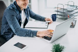 Mann liest Daten am Notebook als Metapher für "Modernes Risikoreporting Klasse statt Masse"