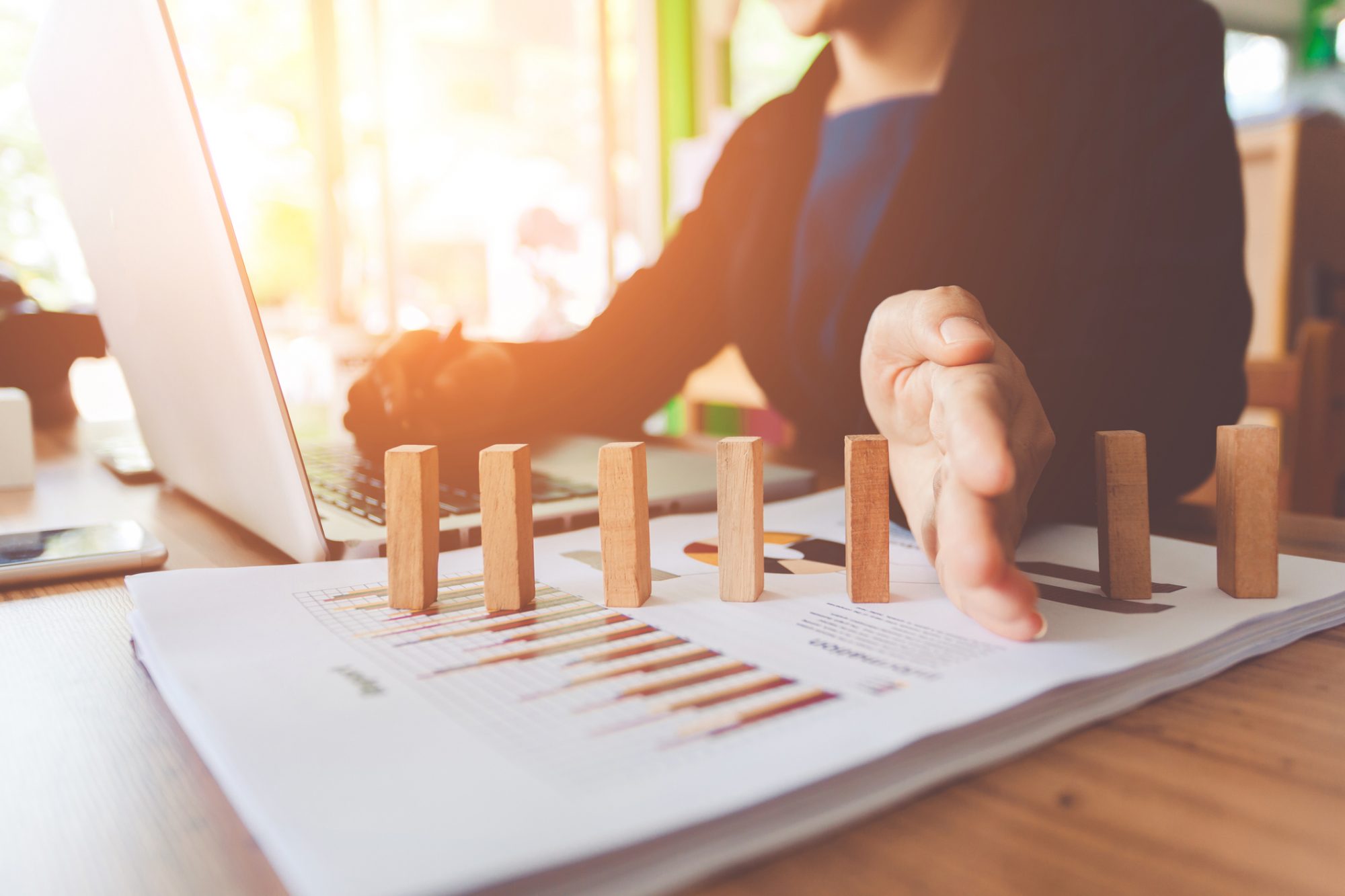 Frau schützt Bausteine vor dem Fallen als Metapher für den Artikel "Dynamic Risk Management Accounting: Empfehlungen"